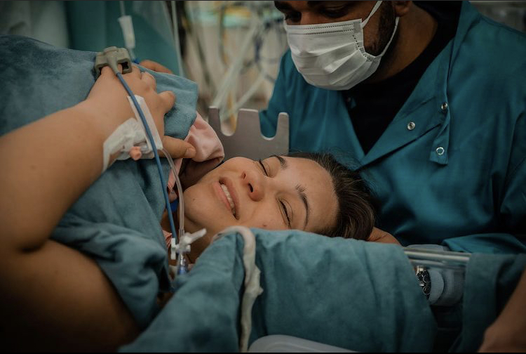 Vrouw houdt baby vast in medische setting.